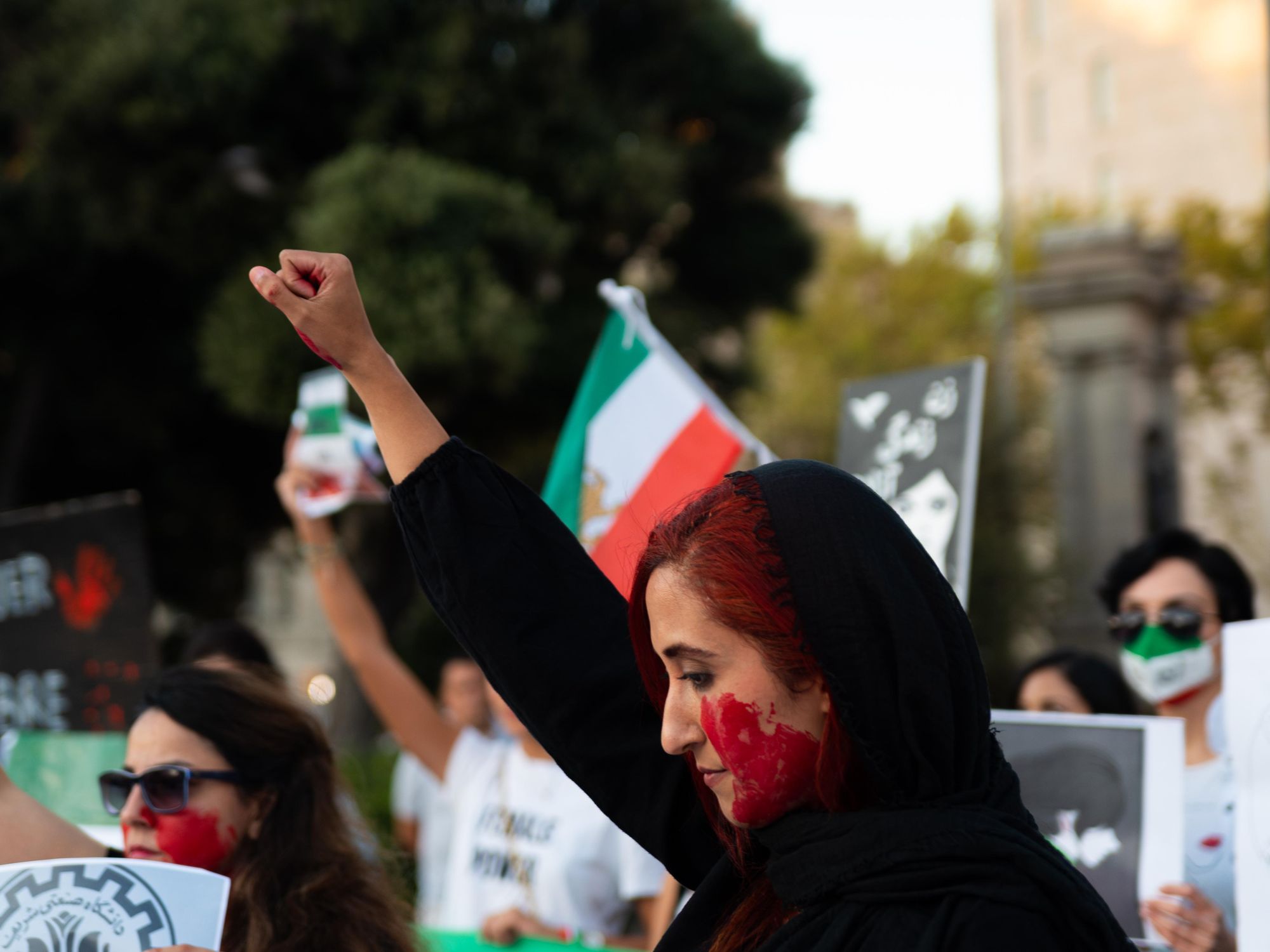 photo of a woman with red paint on her face protesting against iran