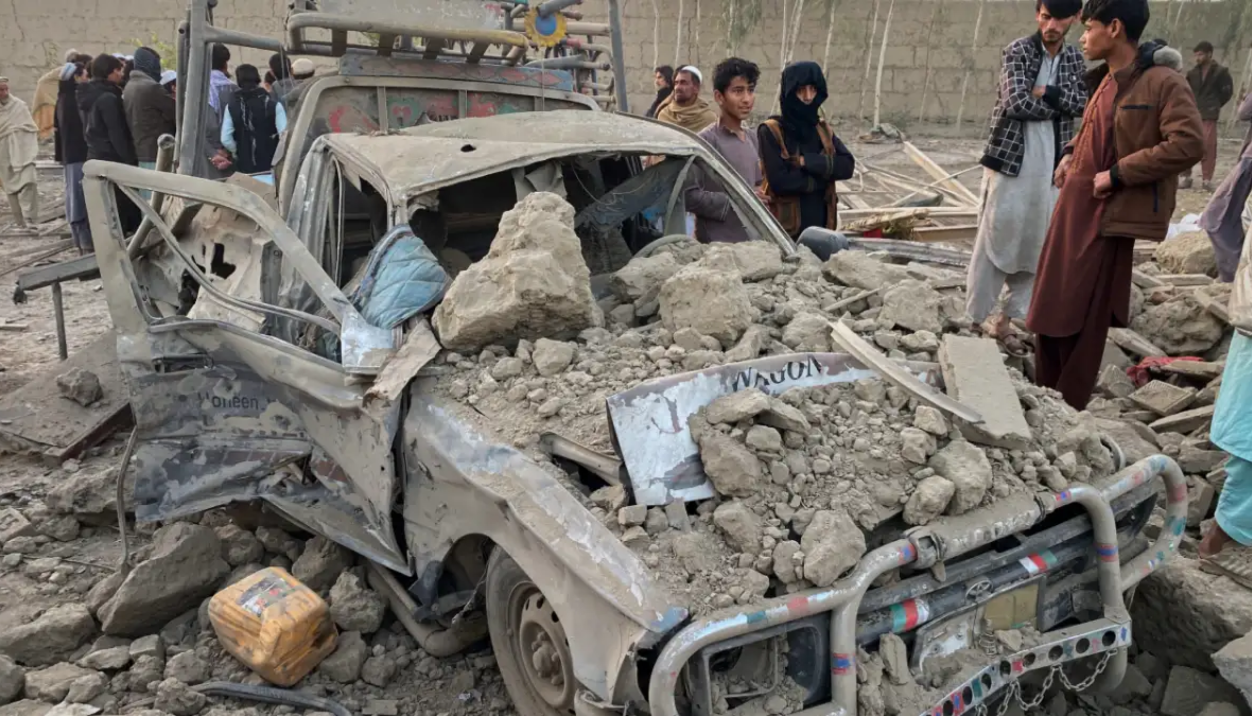 Car destroyed in blast in Afghanistan-Pakistan conflict as civilians inspect damage