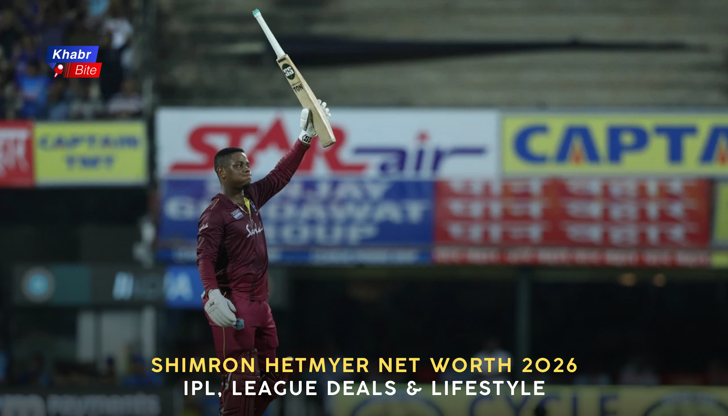 Shimron Hetmyer raising his bat to celebrate a milestone while playing for West Indies during a night cricket match in a packed stadium.