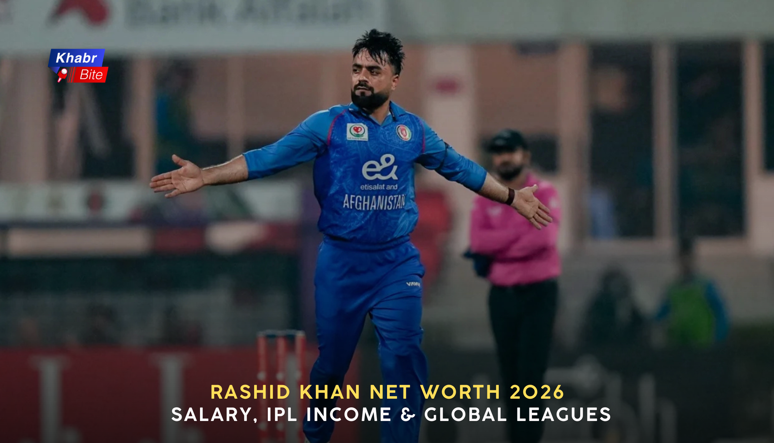 Rashid Khan celebrating a wicket while playing for Afghanistan, wearing blue national team jersey during an international cricket match, arms outstretched.