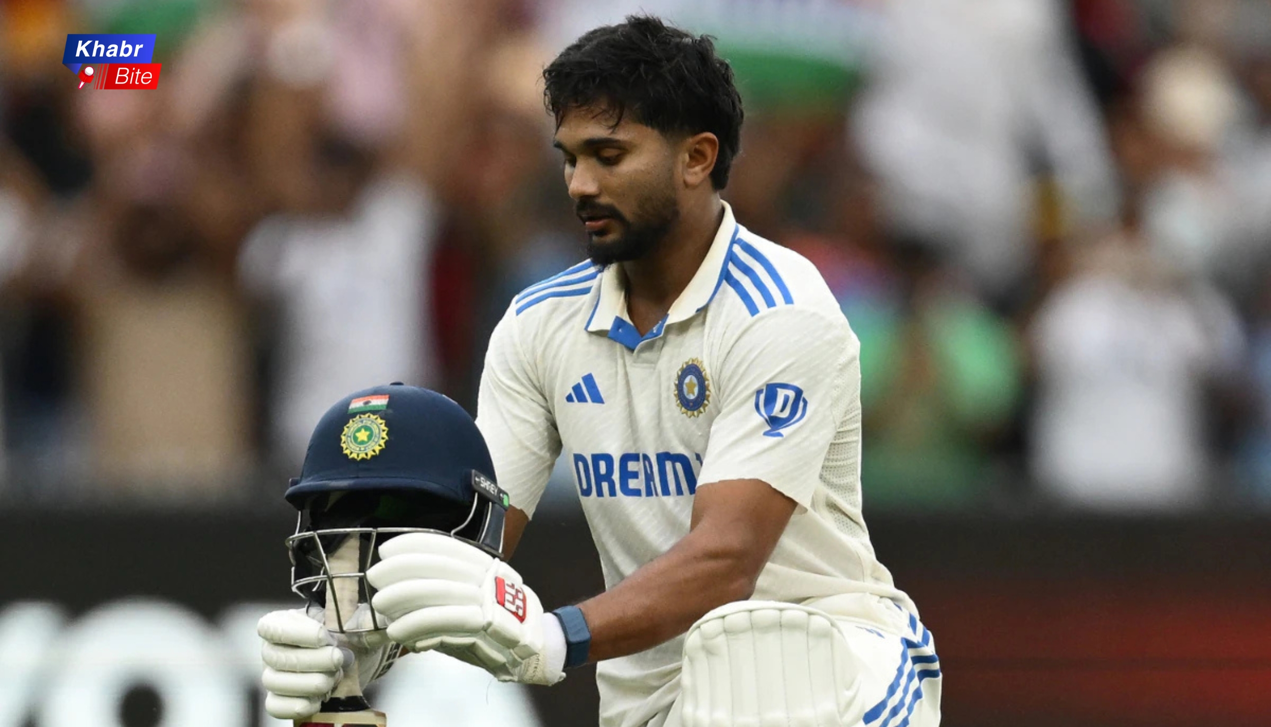 Nitish Kumar Reddy wearing Team India jersey holding helmet during a cricket match