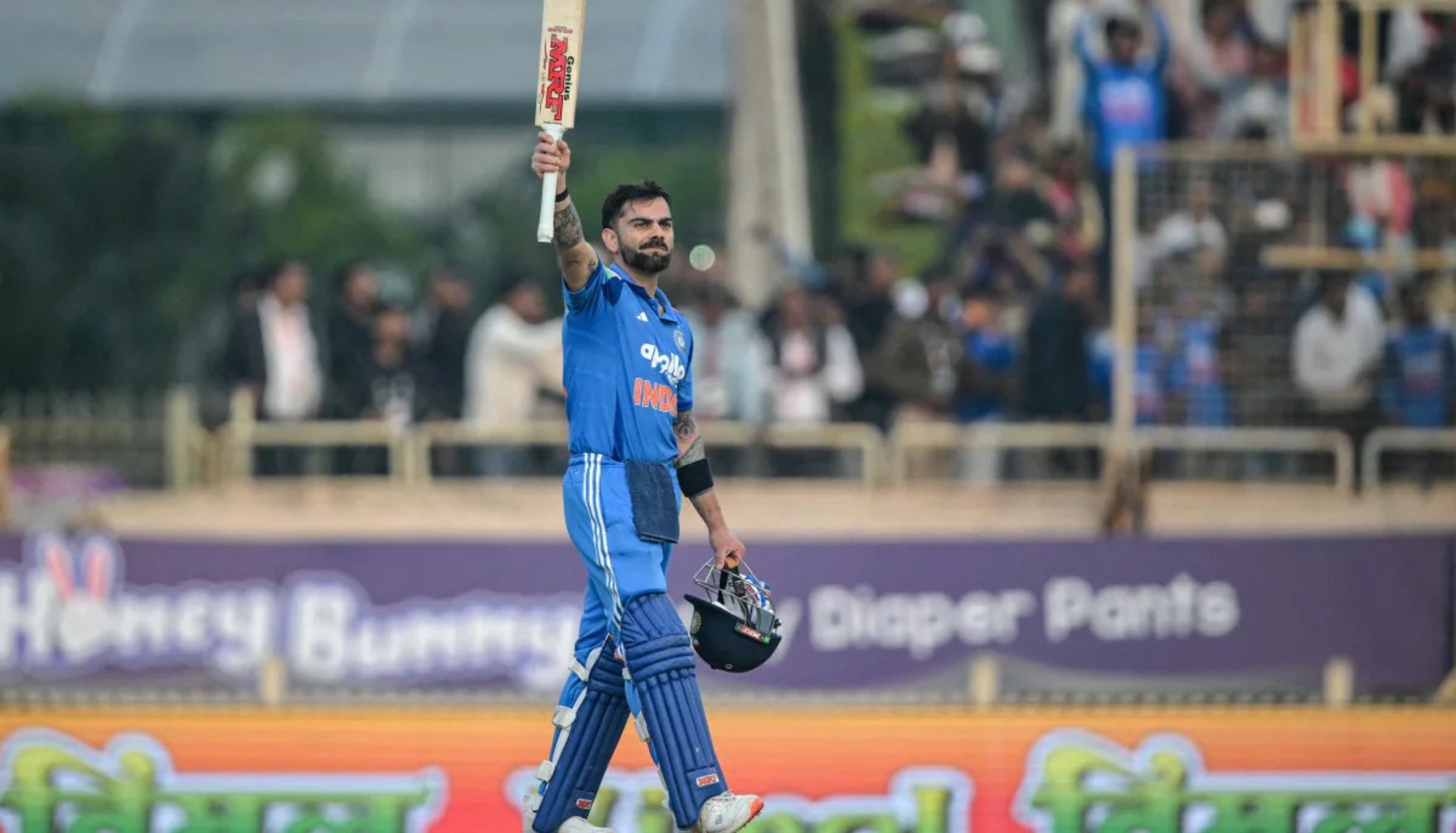 Virat Kohli raises his bat to celebrate a milestone during a match.
